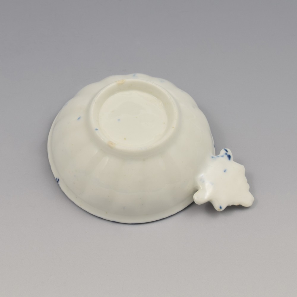 An eighteenth-century Derby soft-paste porcelain circular wine taster featuring hand-painted underglaze blue floral motifs and a shell-moulded handle. View VII