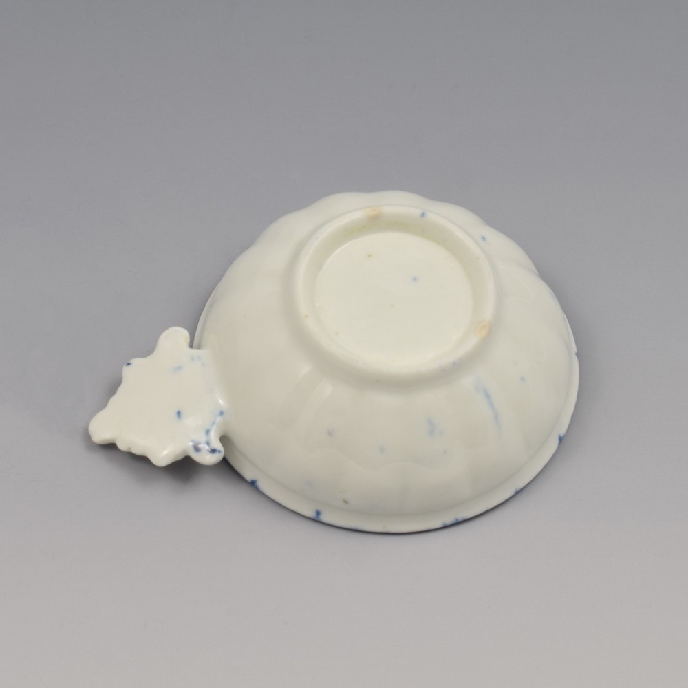 An eighteenth-century Derby soft-paste porcelain circular wine taster featuring hand-painted underglaze blue floral motifs and a shell-moulded handle. View VIII