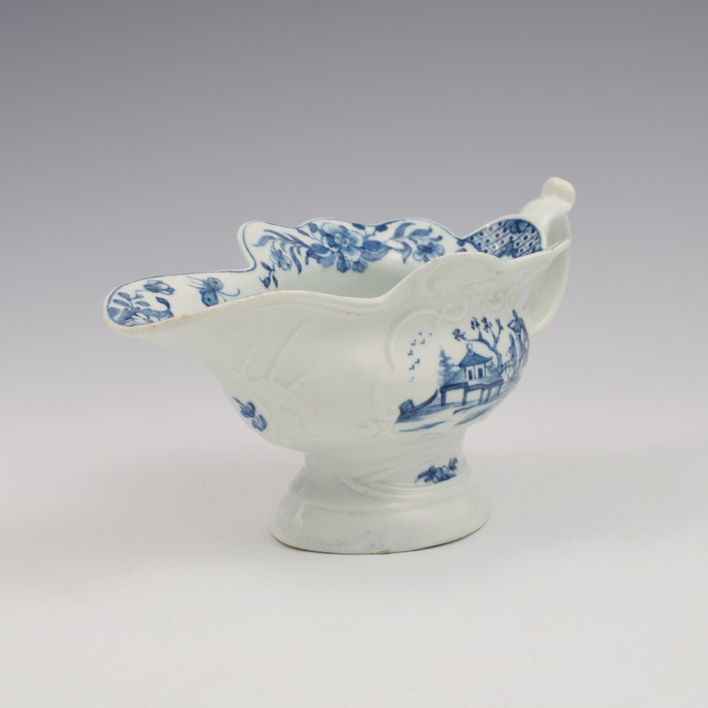 An 18th-century First Period Worcester soft-paste porcelain sauce boat decorated with a hand-painted blue and white chinoiserie landscape motif. View IV
