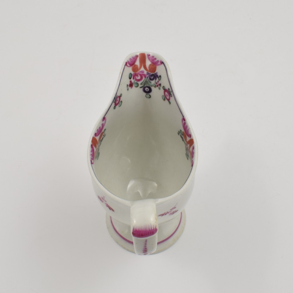 An 18th-century Georgian New Hall white porcelain cream jug featuring a high clip handle, pedestal foot, and hand-painted pink floral motifs. View VII