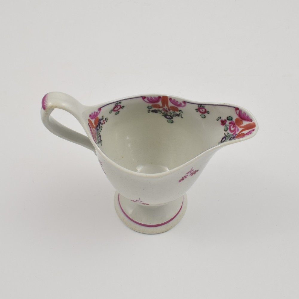An 18th-century Georgian New Hall white porcelain cream jug featuring a high clip handle, pedestal foot, and hand-painted pink floral motifs. View VIII