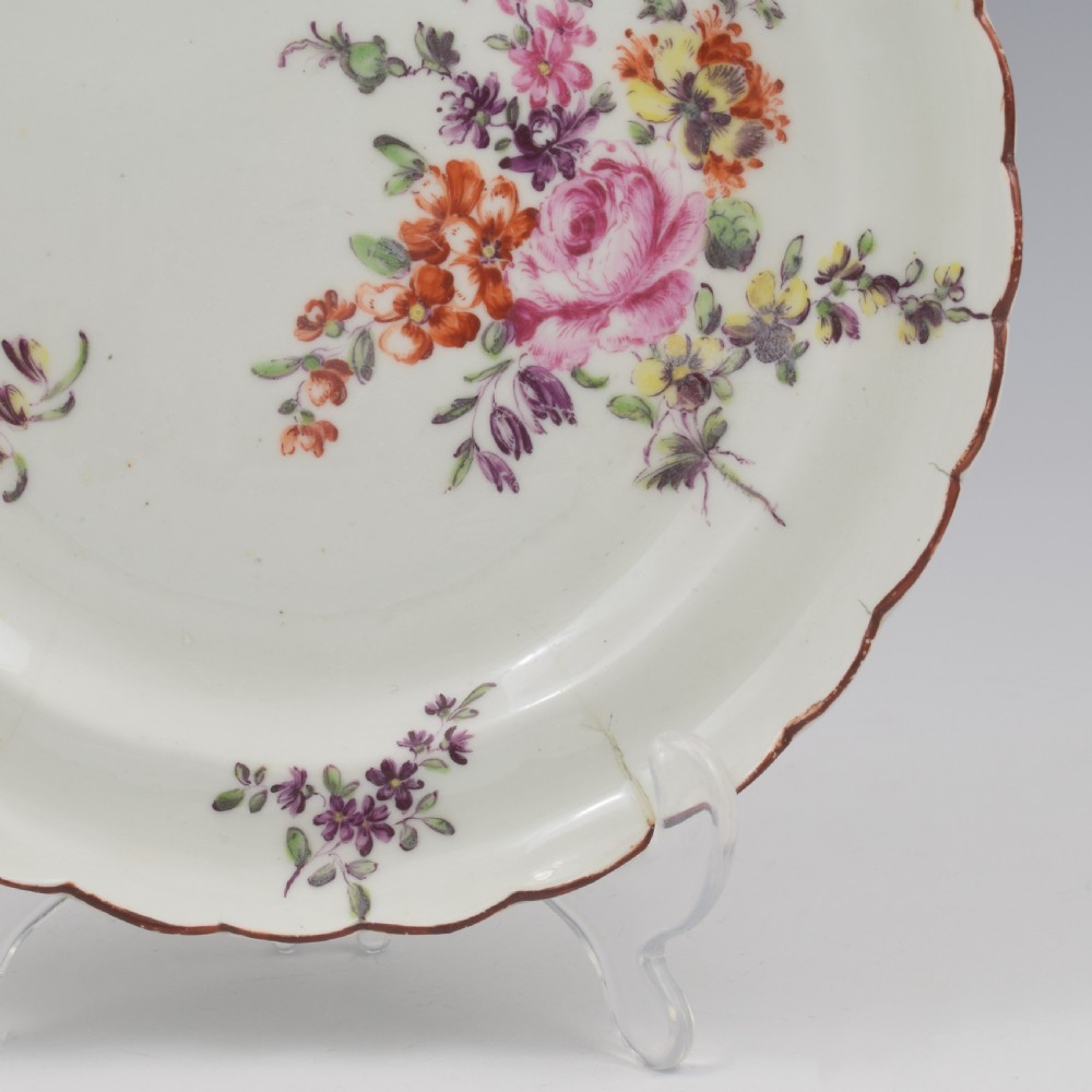 An 18th-century English soft-paste porcelain lobed plate decorated with hand-painted polychrome floral sprays and a brown line rim. View III