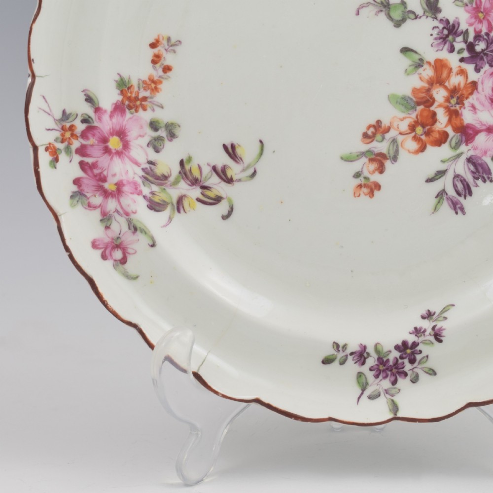 An 18th-century English soft-paste porcelain lobed plate decorated with hand-painted polychrome floral sprays and a brown line rim. View IV