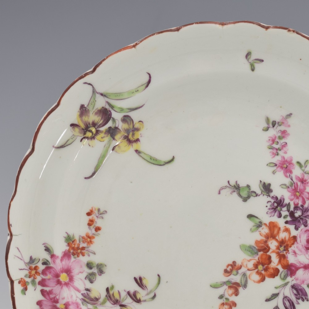 An 18th-century English soft-paste porcelain lobed plate decorated with hand-painted polychrome floral sprays and a brown line rim. View V