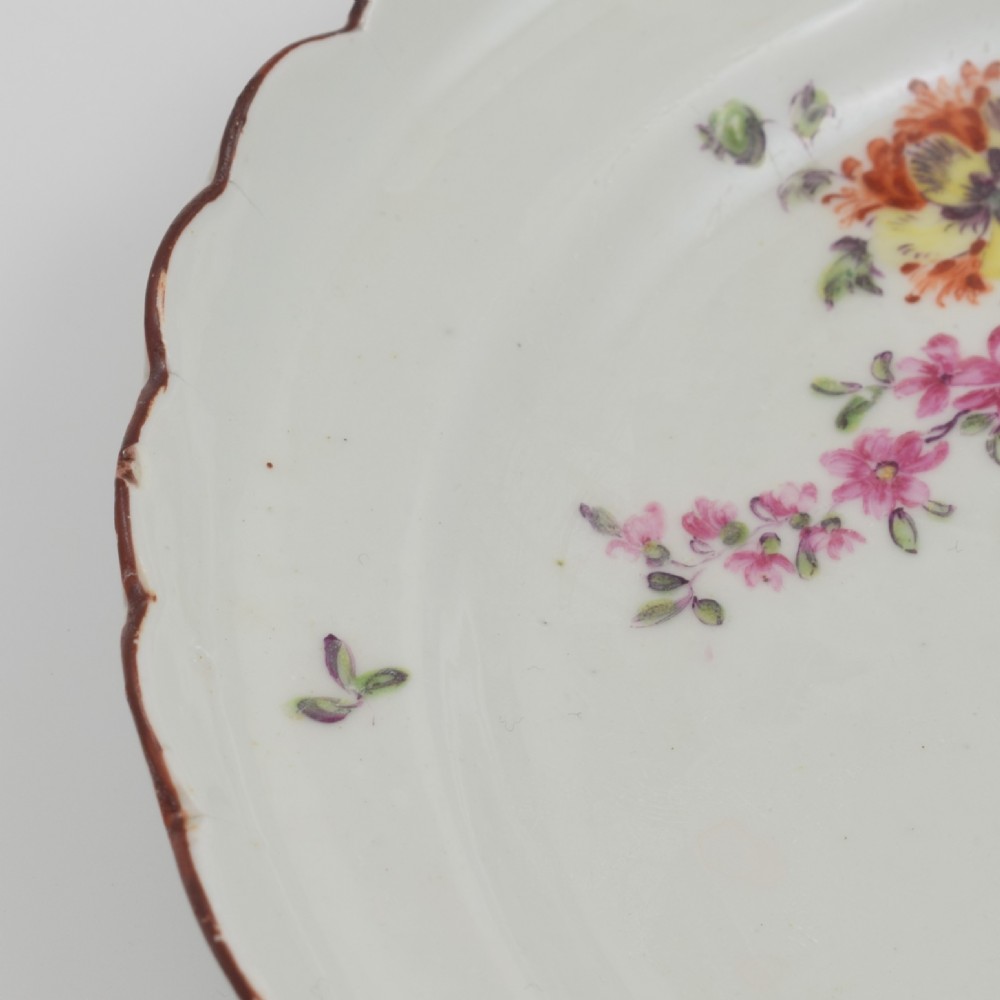 An 18th-century English soft-paste porcelain lobed plate decorated with hand-painted polychrome floral sprays and a brown line rim. View IX