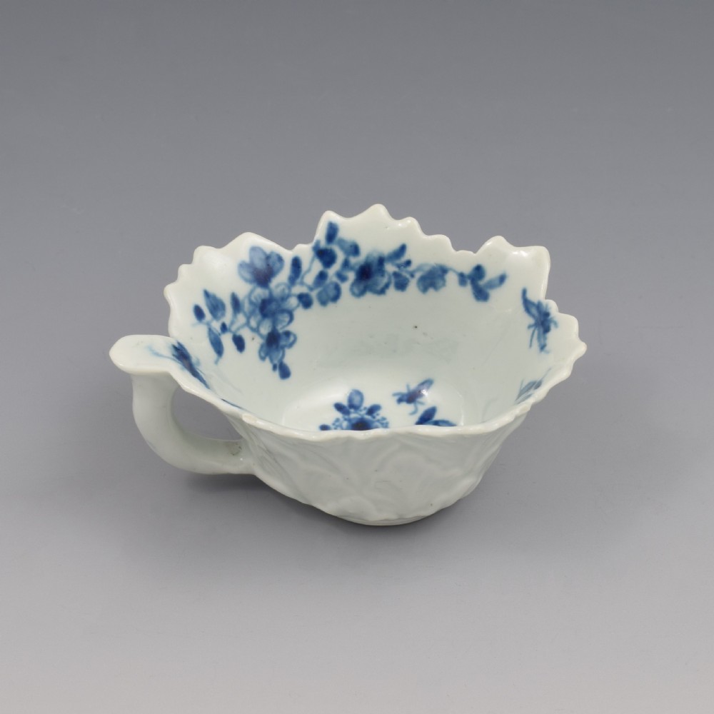 A leaf-shaped soft-paste porcelain butter boat decorated with an underglaze blue floral pattern and serrated edges. View IV