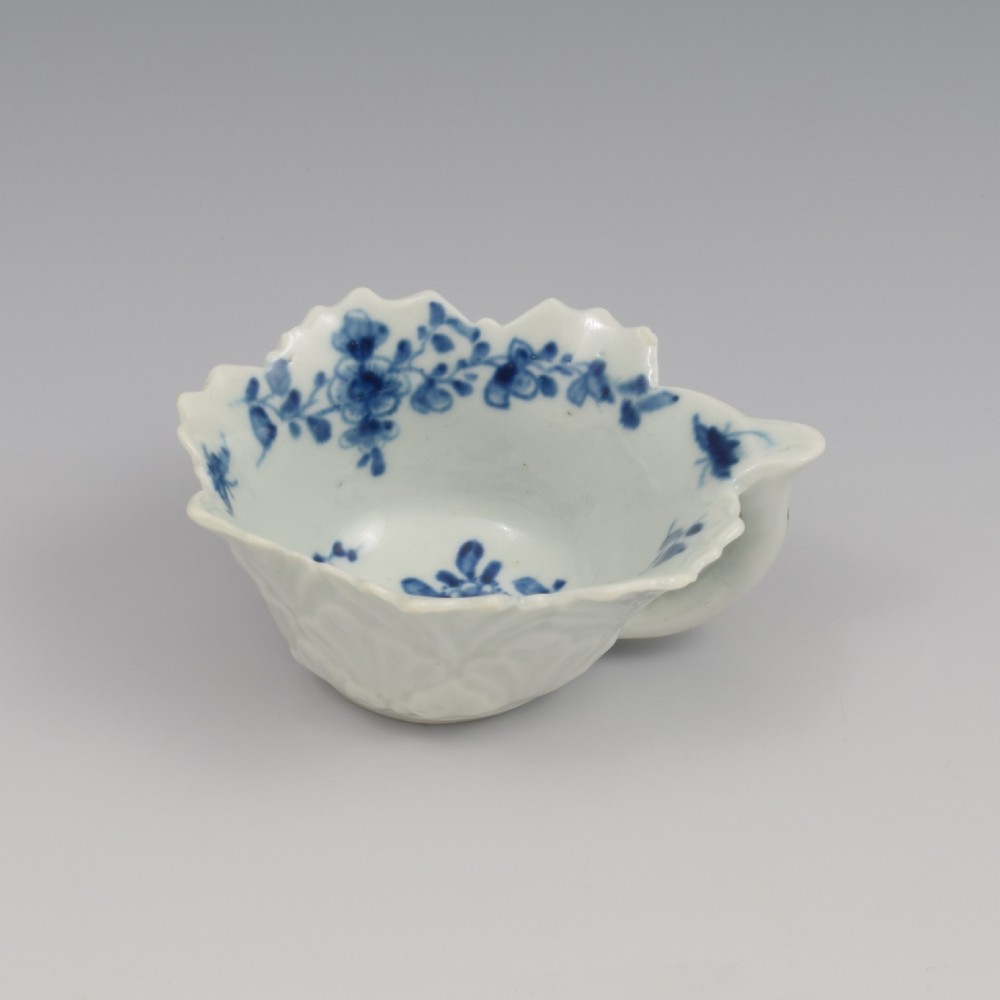 A leaf-shaped soft-paste porcelain butter boat decorated with an underglaze blue floral pattern and serrated edges. View V