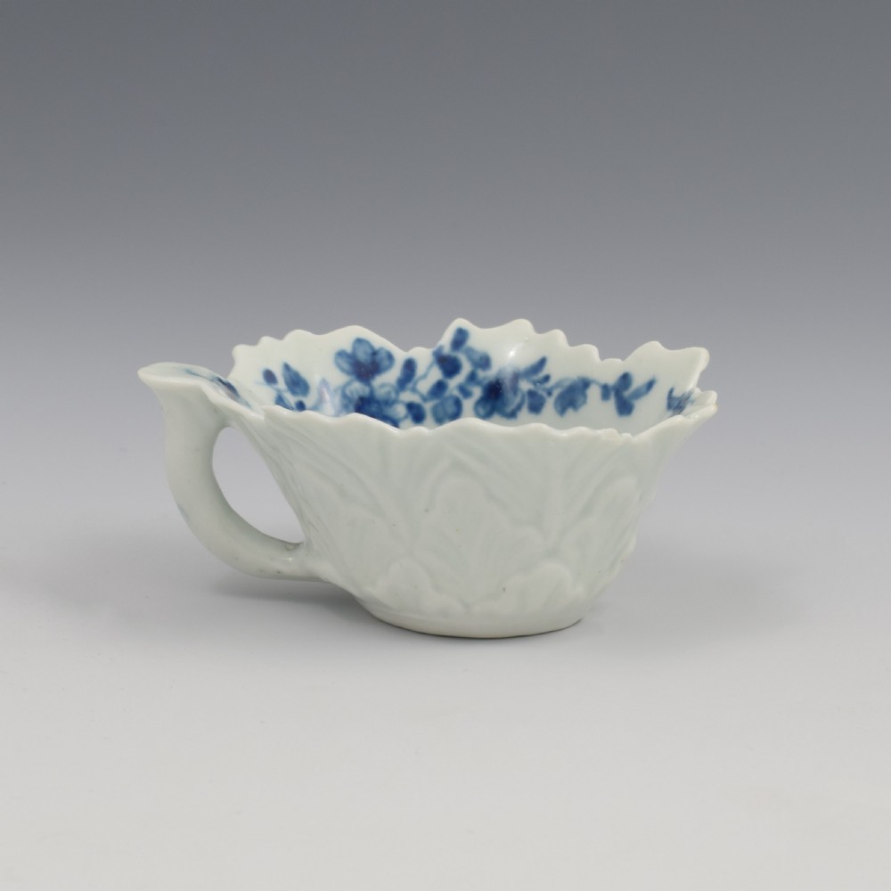 A leaf-shaped soft-paste porcelain butter boat decorated with an underglaze blue floral pattern and serrated edges. View VI