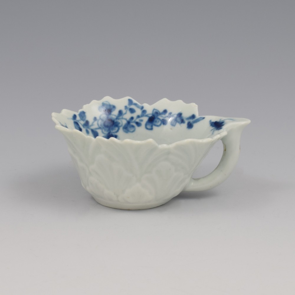 A leaf-shaped soft-paste porcelain butter boat decorated with an underglaze blue floral pattern and serrated edges. View VIII