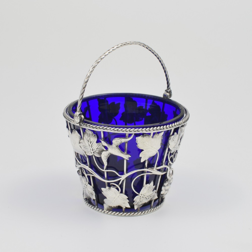 A Georgian sterling silver wirework cream pail featuring botanical motifs and a twisted overhead handle, fitted with a cobalt blue glass liner. View II