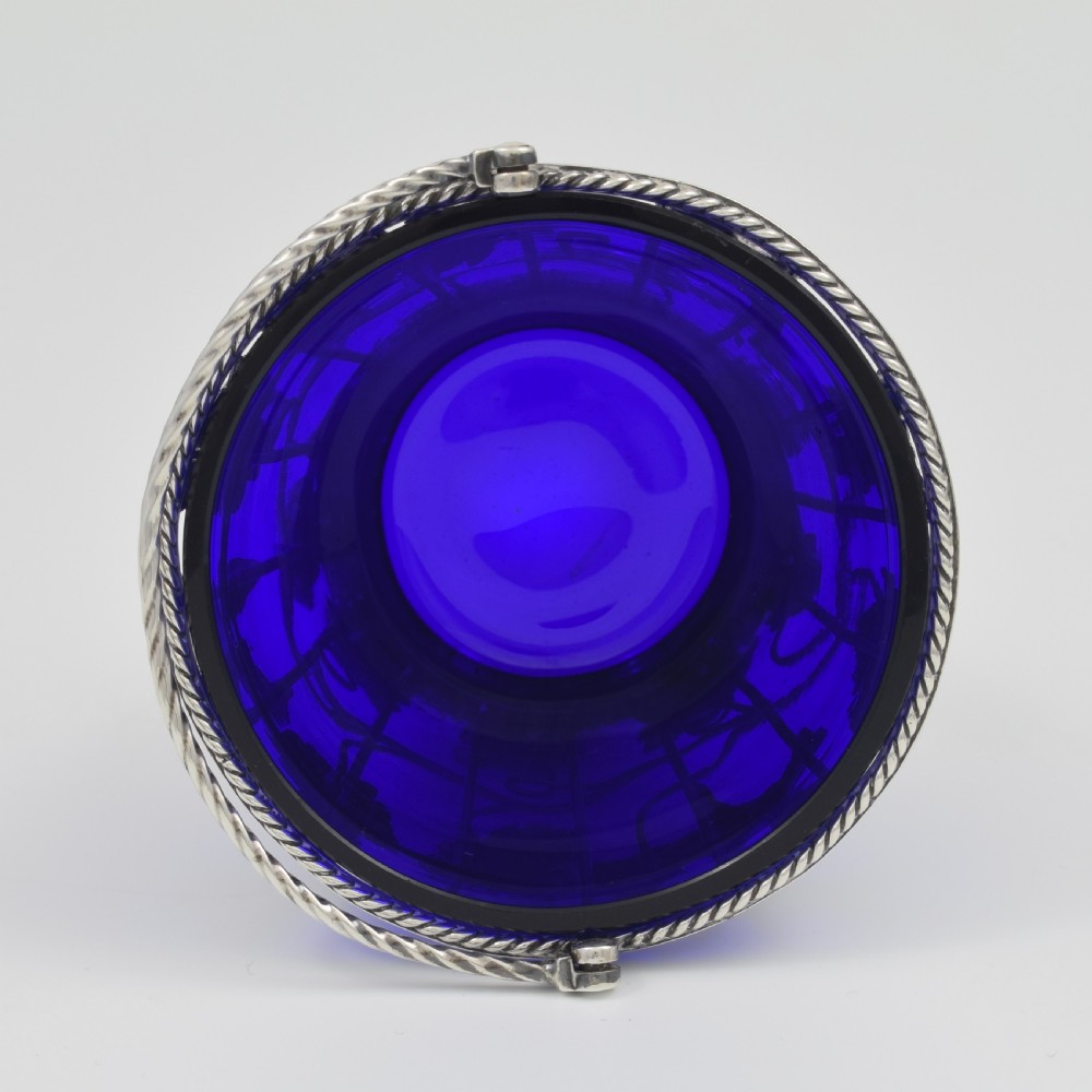 A Georgian sterling silver wirework cream pail featuring botanical motifs and a twisted overhead handle, fitted with a cobalt blue glass liner. View XI