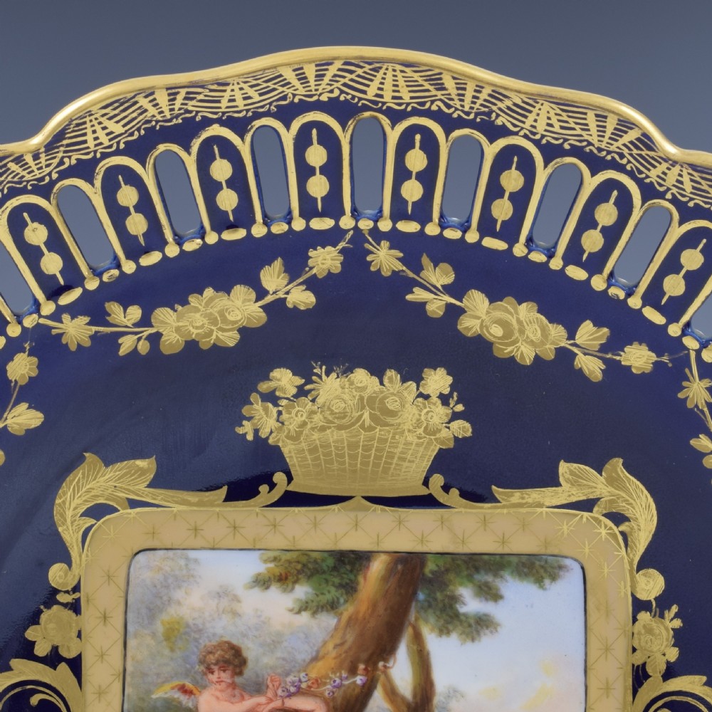 A cobalt blue and gilt porcelain cabinet plate featuring a pierced reticulated border and a central hand-painted square scene of Cupid and Psyche. View IV