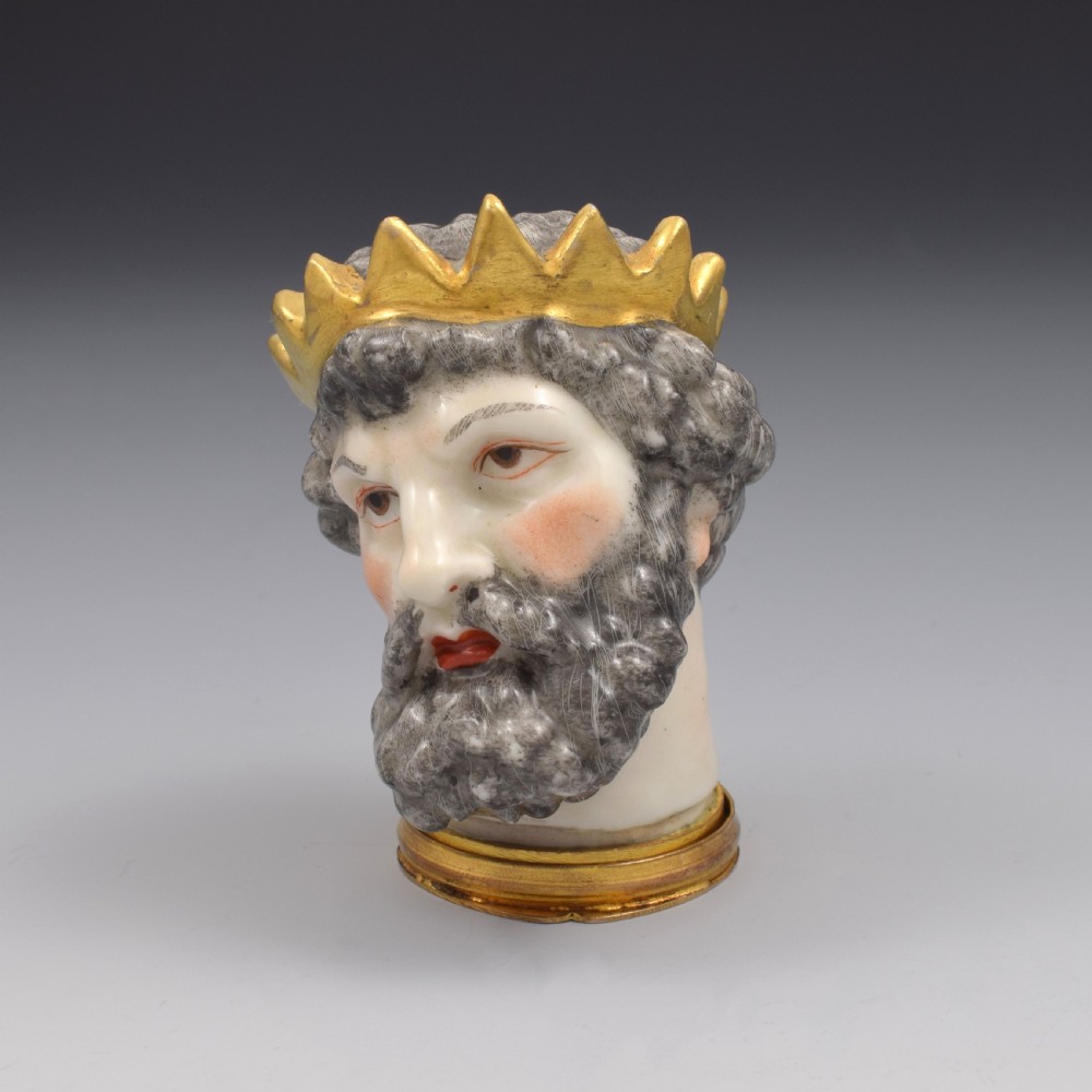 A French porcelain bonbonniere crafted in the shape of the bearded god Neptune with a gilt crown and mounted on a brass rim base.