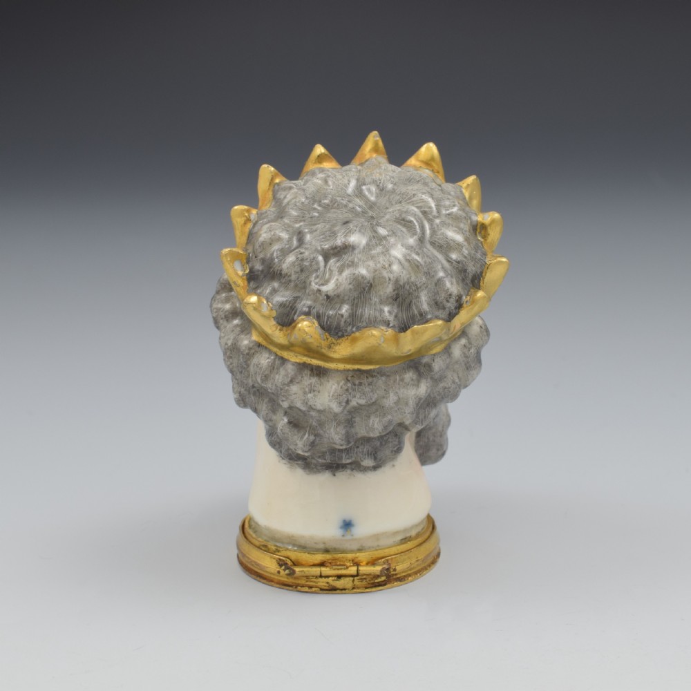 A French porcelain bonbonniere crafted in the shape of the bearded god Neptune with a gilt crown and mounted on a brass rim base. View V