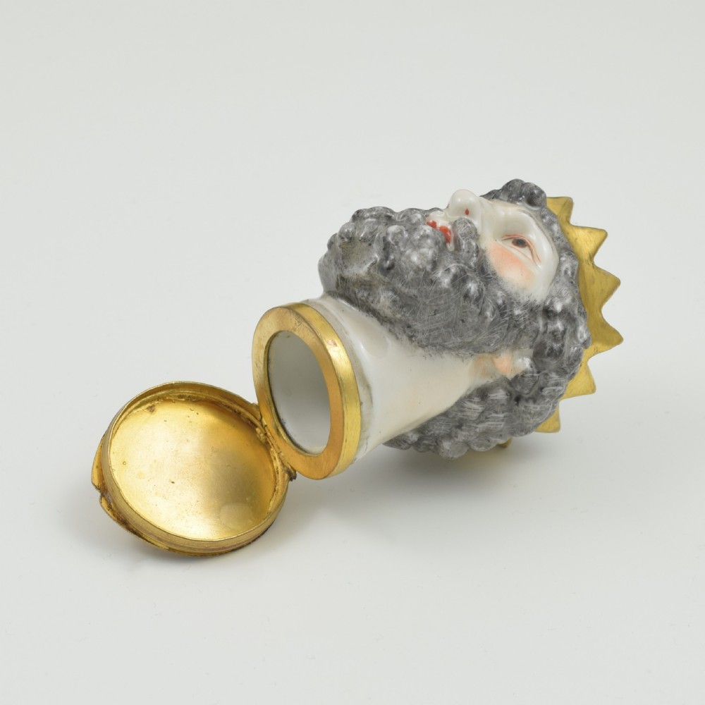 A French porcelain bonbonniere crafted in the shape of the bearded god Neptune with a gilt crown and mounted on a brass rim base. View X