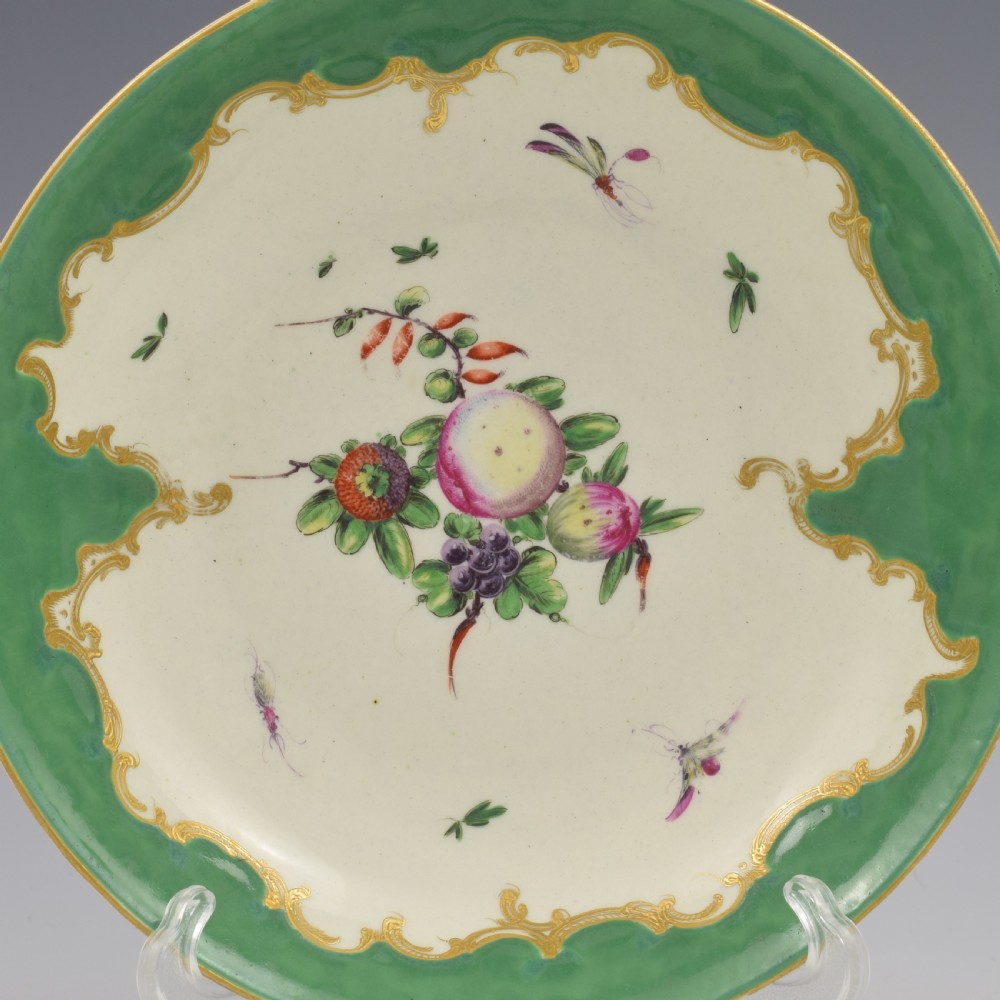 A circular eighteenth-century porcelain dish featuring an apple green border with gilded rococo scrolling surrounding a white centre painted with fruit and insects. View II