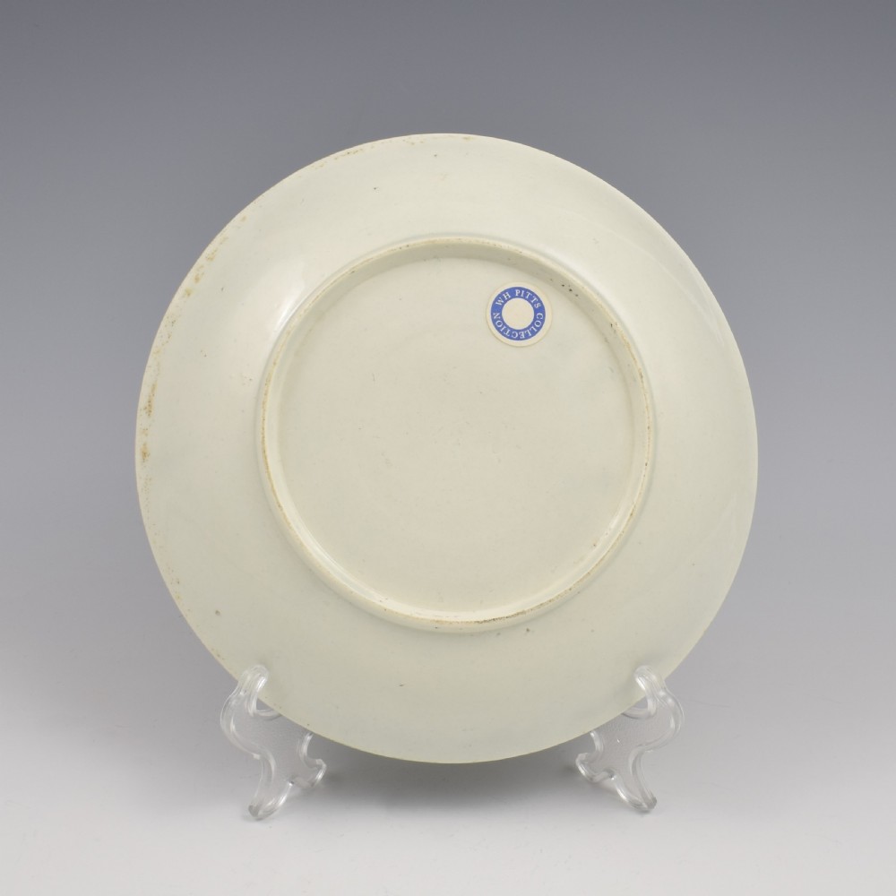 A circular eighteenth-century porcelain dish featuring an apple green border with gilded rococo scrolling surrounding a white centre painted with fruit and insects. View IV