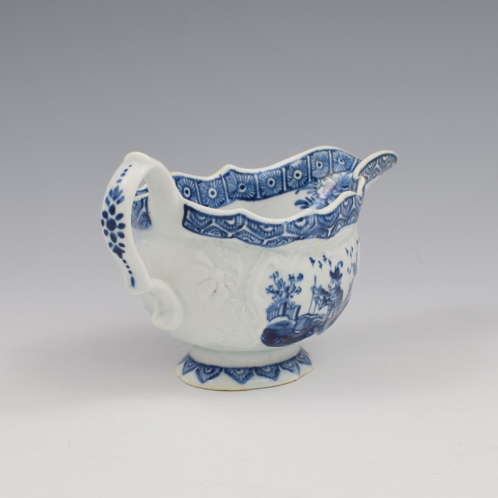 An eighteenth-century English soft-paste porcelain sauce boat decorated with underglaze cobalt blue Chinoiserie figures, a scalloped rim, and a molded handle. View III