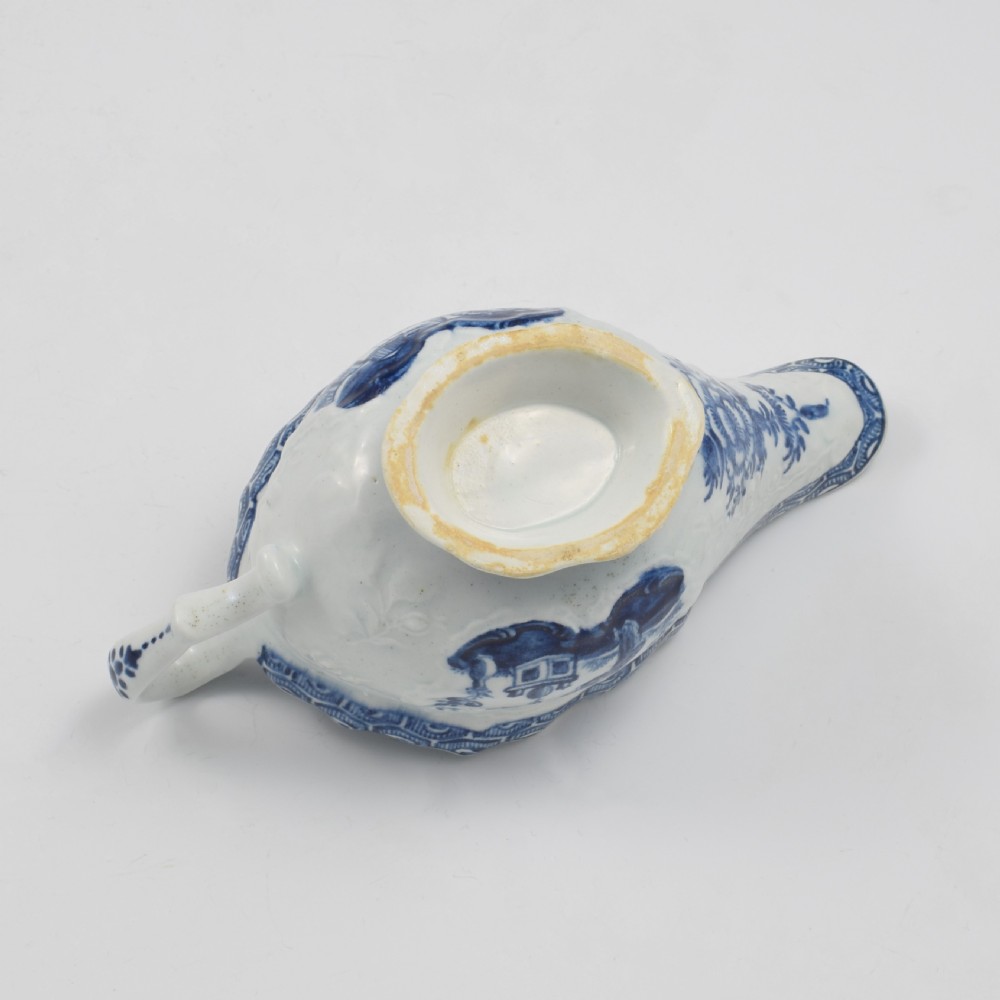 An eighteenth-century English soft-paste porcelain sauce boat decorated with underglaze cobalt blue Chinoiserie figures, a scalloped rim, and a molded handle. View XI