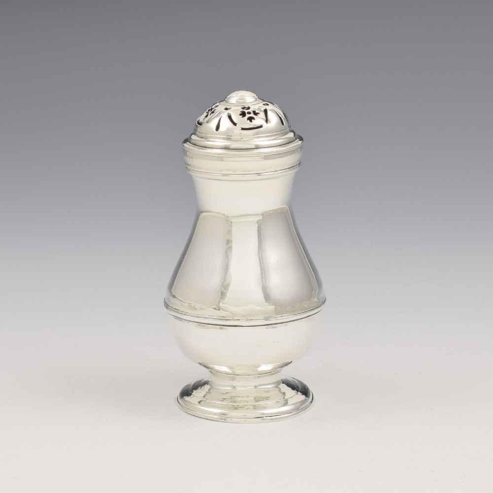 A George I sterling silver pounce pot with a faceted baluster body, stepped pedestal base, pierced dome cover, and engraved initials. View V