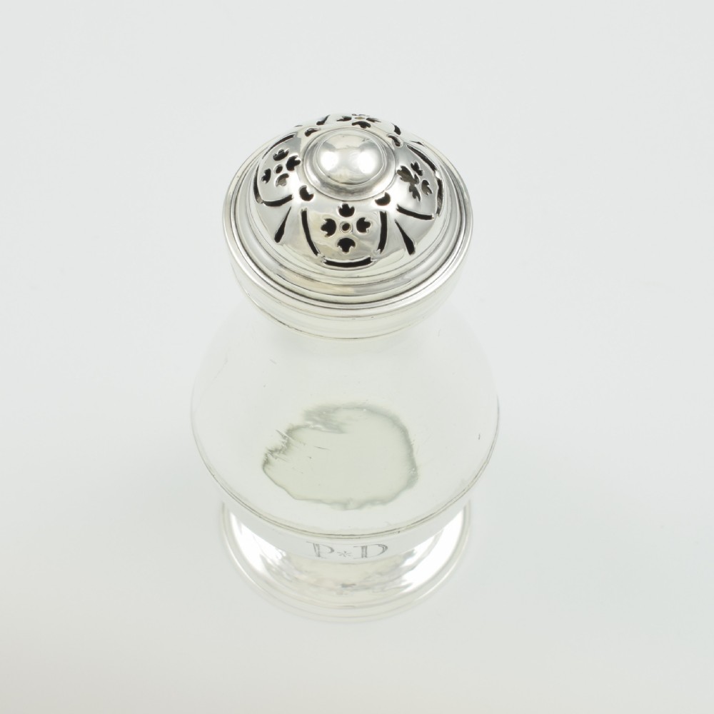 A George I sterling silver pounce pot with a faceted baluster body, stepped pedestal base, pierced dome cover, and engraved initials. View VI