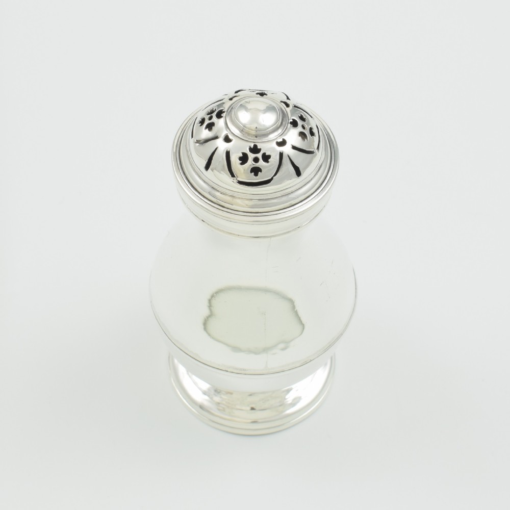 A George I sterling silver pounce pot with a faceted baluster body, stepped pedestal base, pierced dome cover, and engraved initials. View VII