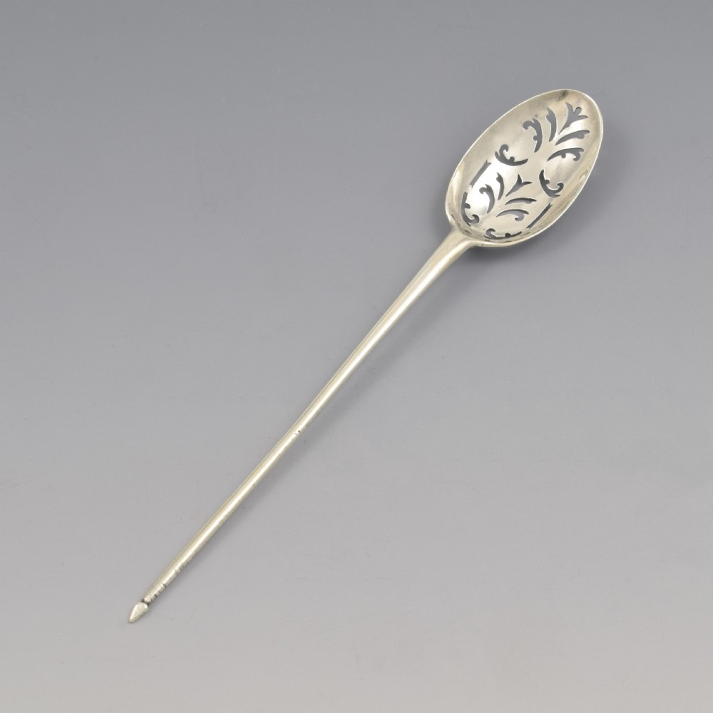 A George II sterling silver mote spoon featuring a pierced oval bowl with scrollwork fretwork and a long tapered spike stem.