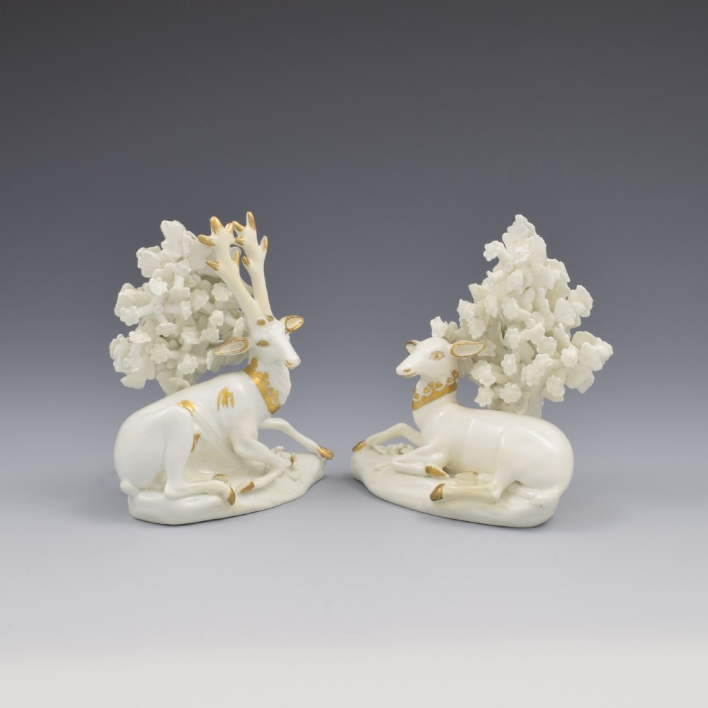 A pair of white glazed porcelain figures representing a recumbent stag and doe with gilded accents set against floral bocage tree backgrounds. View II