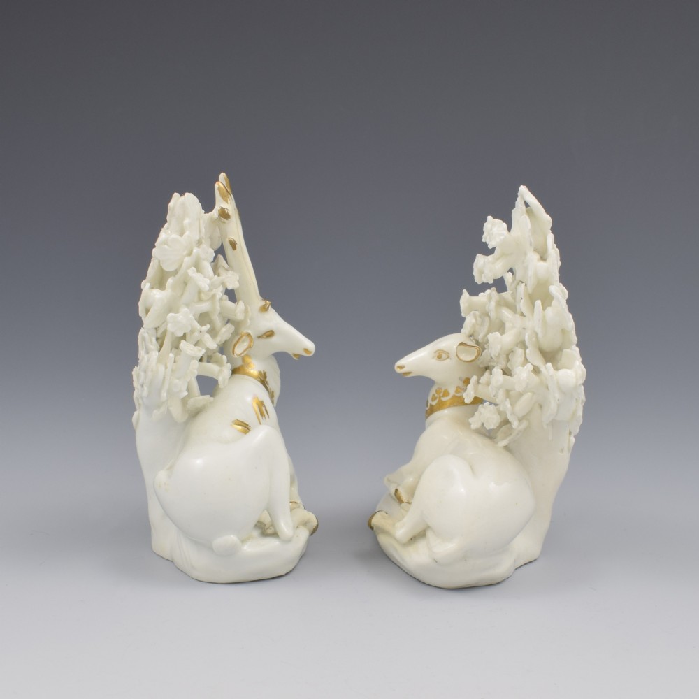 A pair of white glazed porcelain figures representing a recumbent stag and doe with gilded accents set against floral bocage tree backgrounds. View III