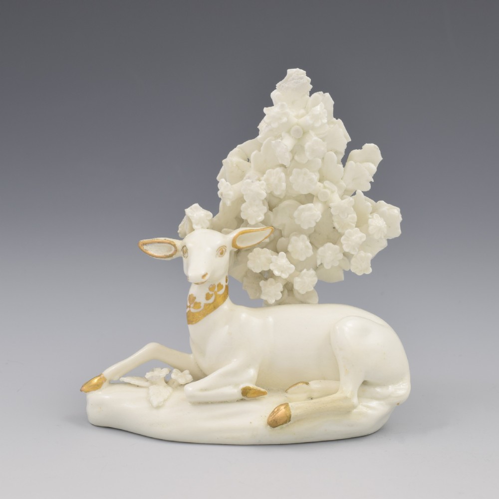A pair of white glazed porcelain figures representing a recumbent stag and doe with gilded accents set against floral bocage tree backgrounds. View XI