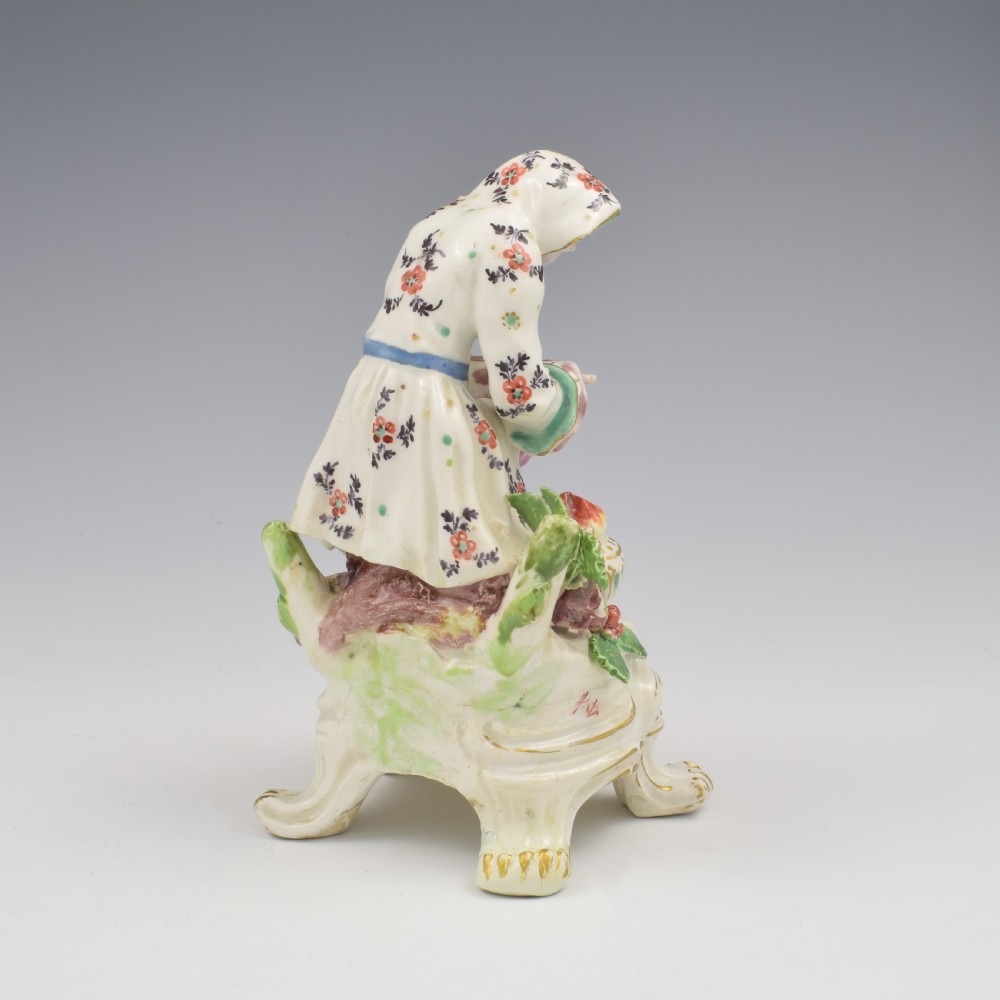 An 18th-century Bow porcelain figure representing Winter, featuring a hooded figure seated on a gilt scrollwork base warming hands over a brazier. View IV