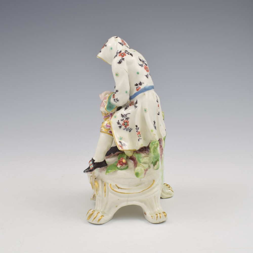 An 18th-century Bow porcelain figure representing Winter, featuring a hooded figure seated on a gilt scrollwork base warming hands over a brazier. View VII