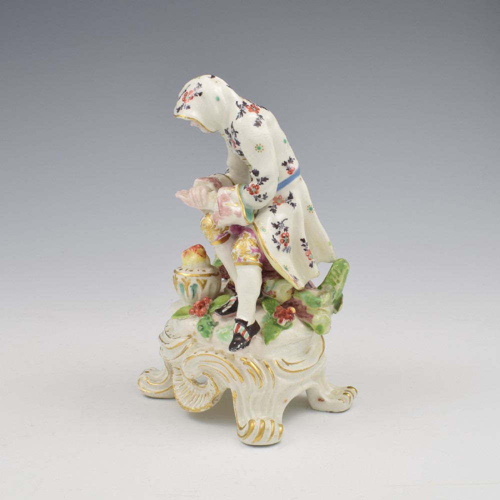 An 18th-century Bow porcelain figure representing Winter, featuring a hooded figure seated on a gilt scrollwork base warming hands over a brazier. View VIII