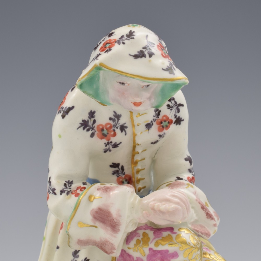 An 18th-century Bow porcelain figure representing Winter, featuring a hooded figure seated on a gilt scrollwork base warming hands over a brazier. View XI