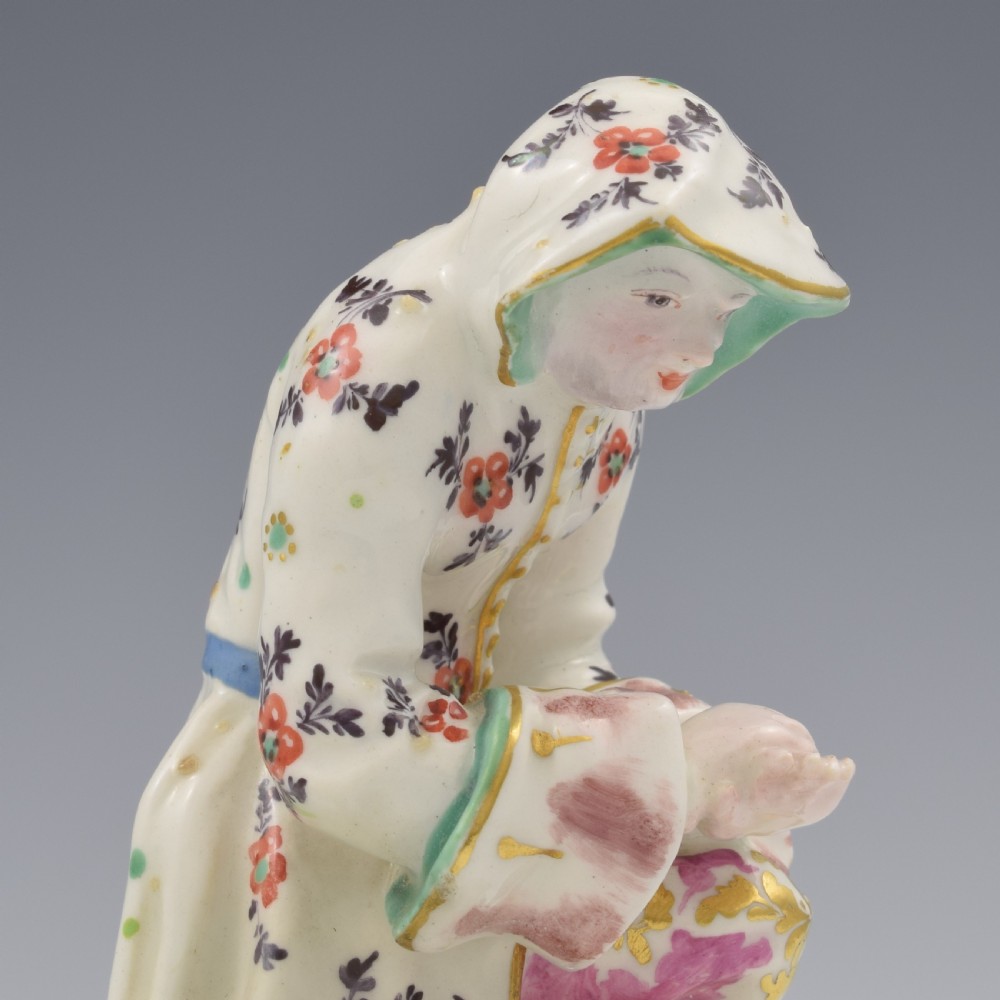 An 18th-century Bow porcelain figure representing Winter, featuring a hooded figure seated on a gilt scrollwork base warming hands over a brazier. View XII