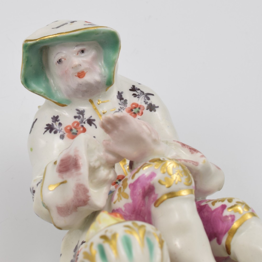 An 18th-century Bow porcelain figure representing Winter, featuring a hooded figure seated on a gilt scrollwork base warming hands over a brazier. View XIII
