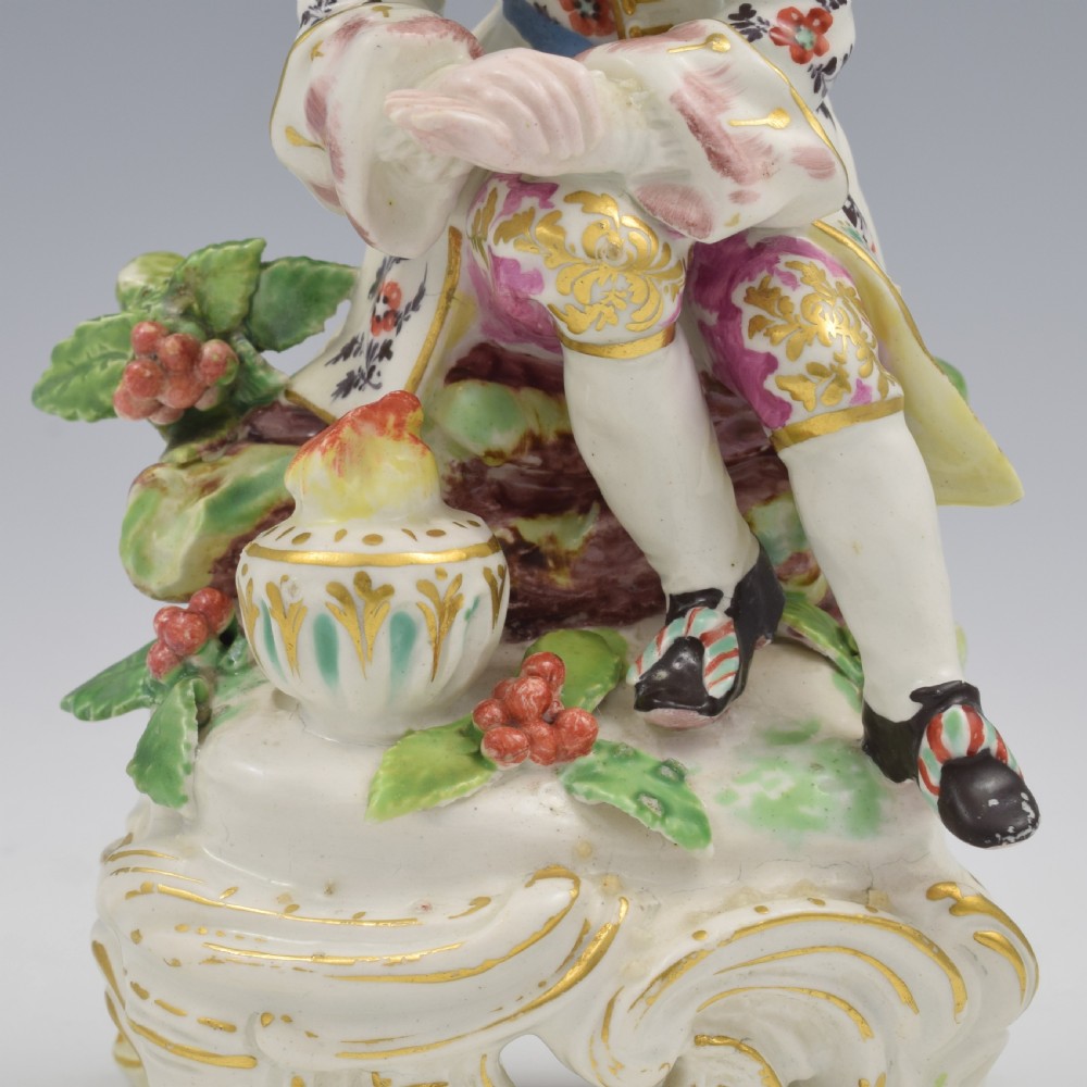 An 18th-century Bow porcelain figure representing Winter, featuring a hooded figure seated on a gilt scrollwork base warming hands over a brazier. View XIV