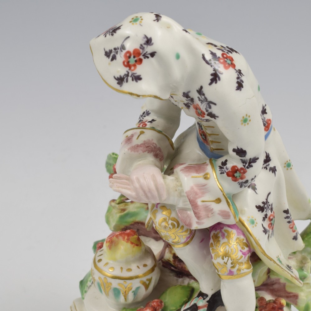 An 18th-century Bow porcelain figure representing Winter, featuring a hooded figure seated on a gilt scrollwork base warming hands over a brazier. View XVI