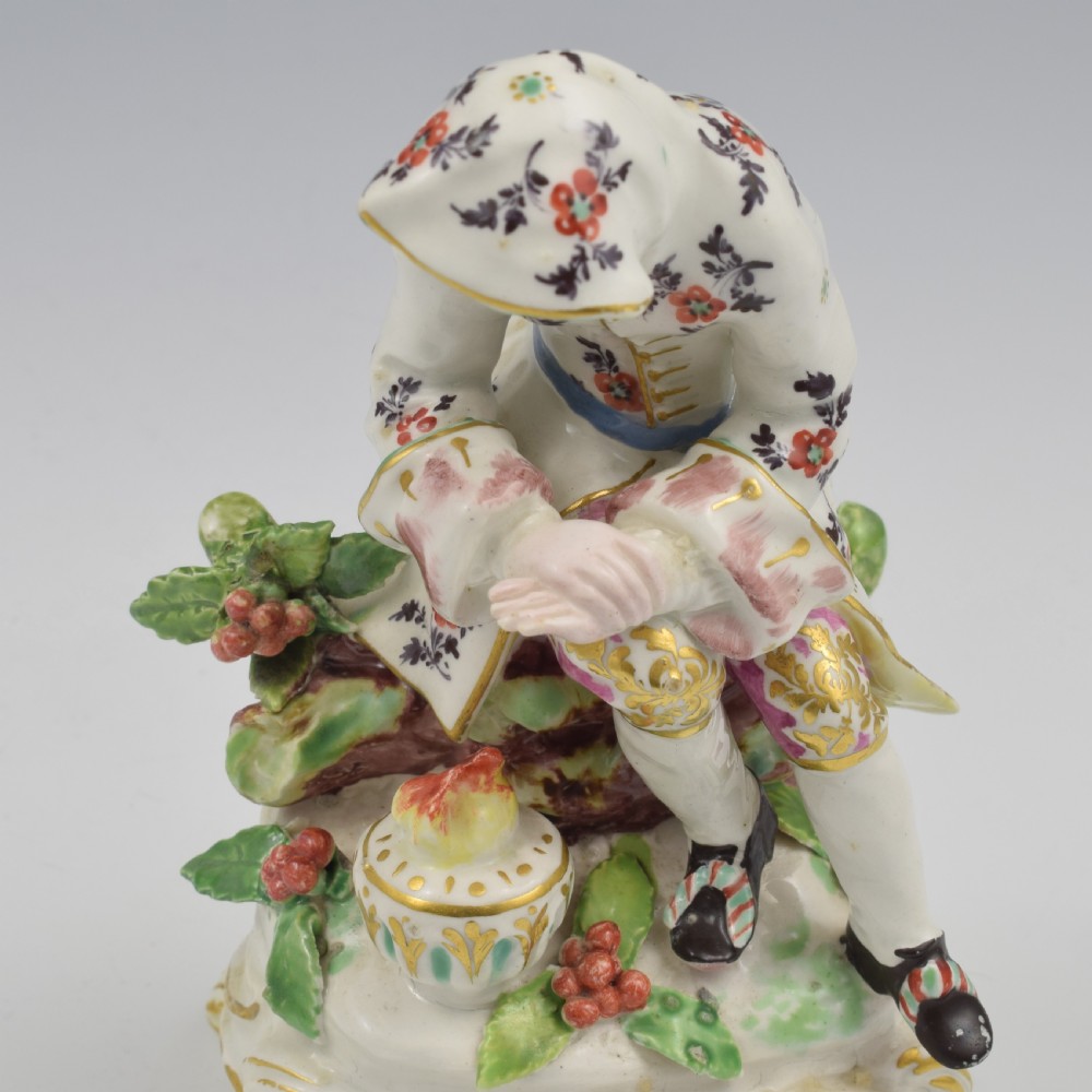 An 18th-century Bow porcelain figure representing Winter, featuring a hooded figure seated on a gilt scrollwork base warming hands over a brazier. View XVII