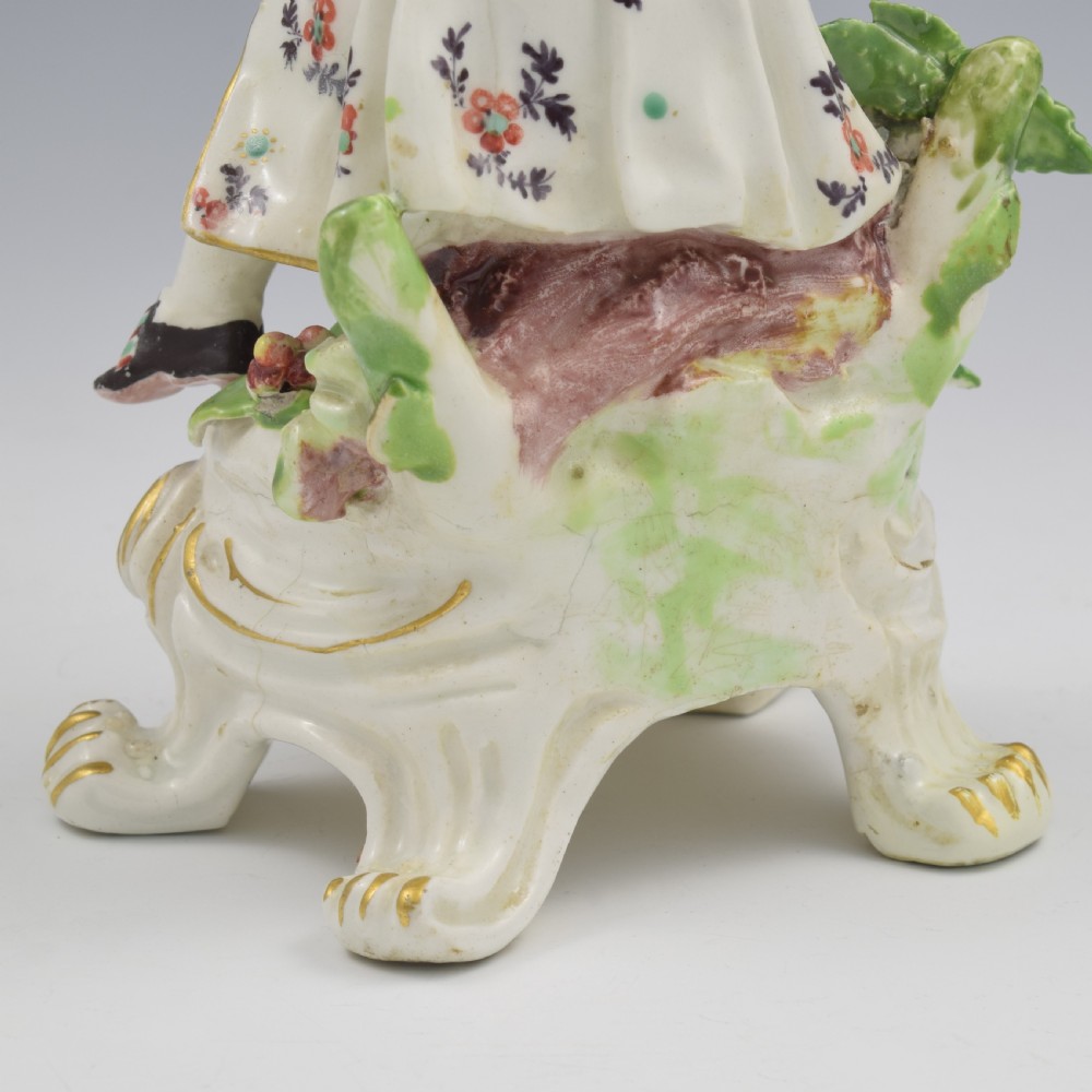 An 18th-century Bow porcelain figure representing Winter, featuring a hooded figure seated on a gilt scrollwork base warming hands over a brazier. View XX