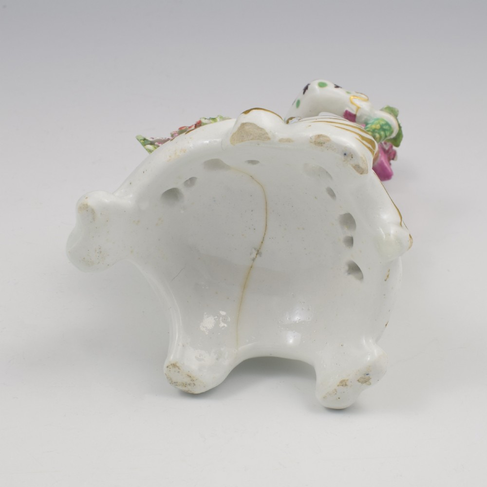 An 18th-century Bow soft-paste porcelain figure depicting an allegorical youth standing beside floral bocage on a pierced gilded scroll base. View IX