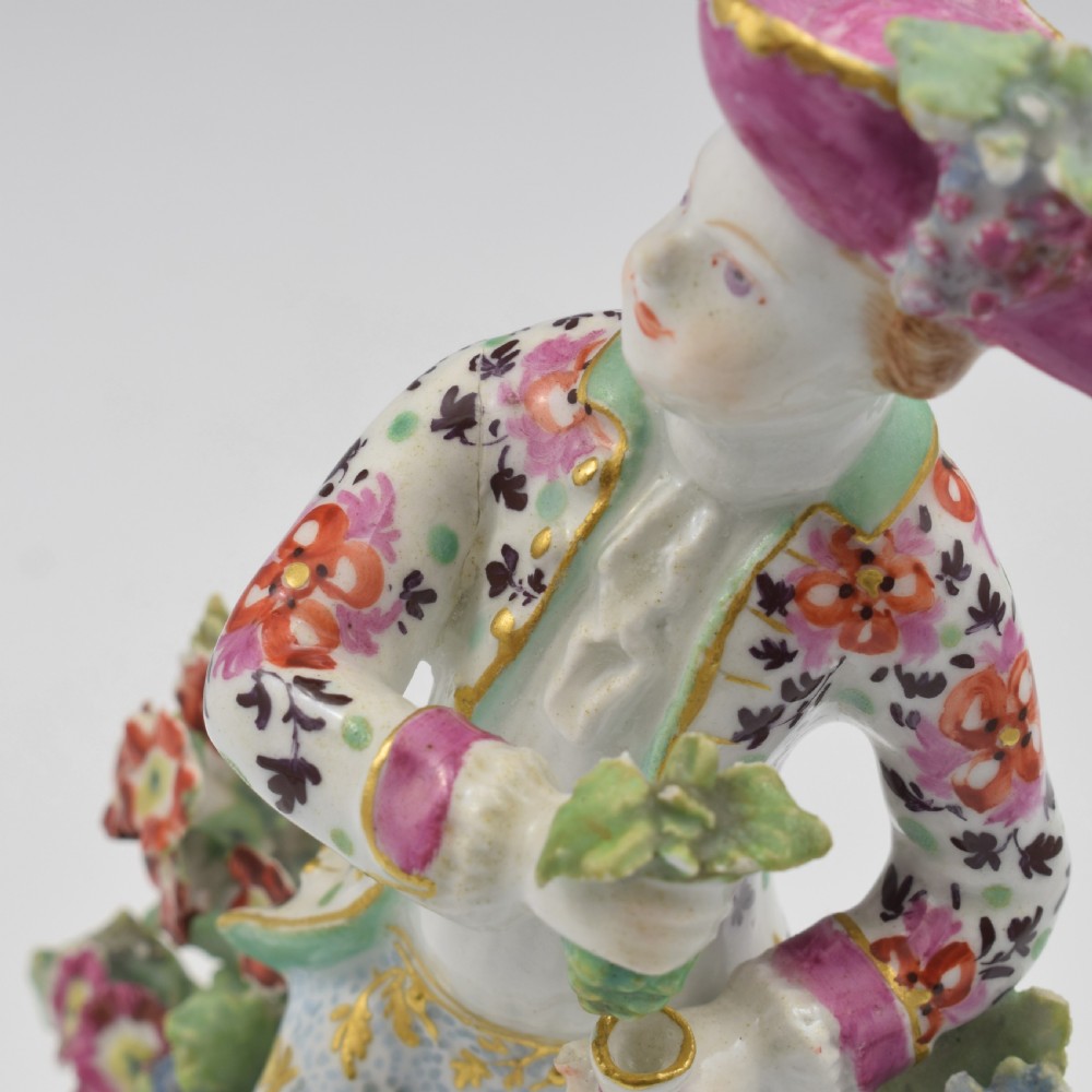 An 18th-century Bow soft-paste porcelain figure depicting an allegorical youth standing beside floral bocage on a pierced gilded scroll base. View XI