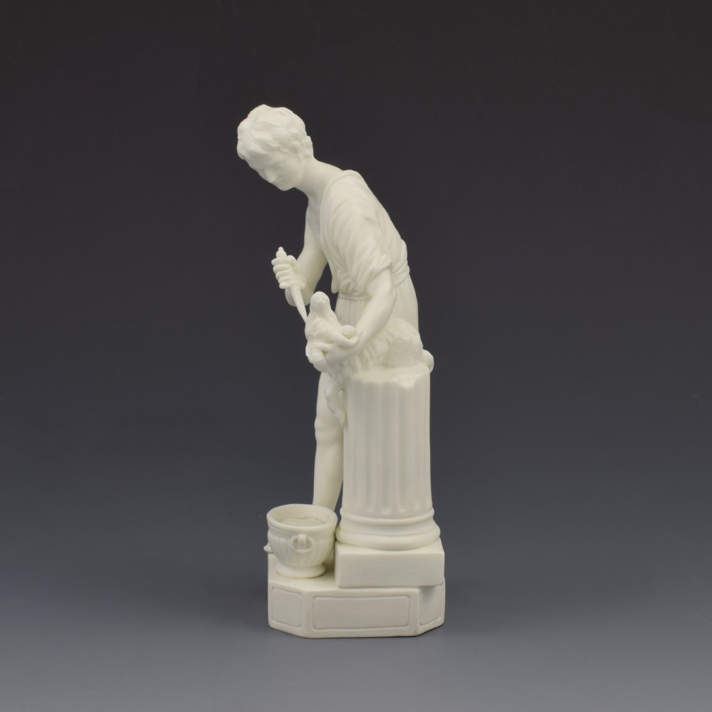 An 18th-century Neoclassical Derby bisque porcelain figure depicting a youth in draped clothing standing beside an altar with a goat. View III