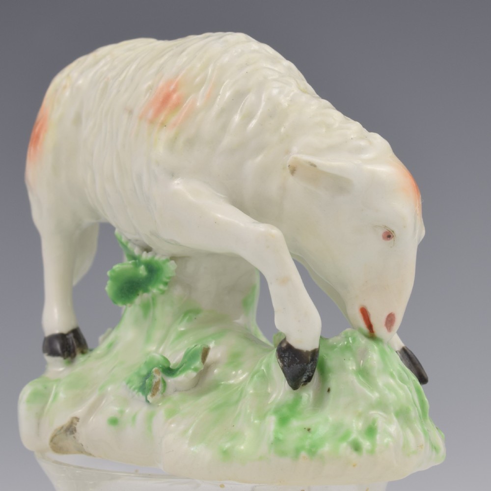 An 18th-century Derby porcelain figure depicting a white grazing ewe with orange flecks on a green leaf-patterned base. View XIII