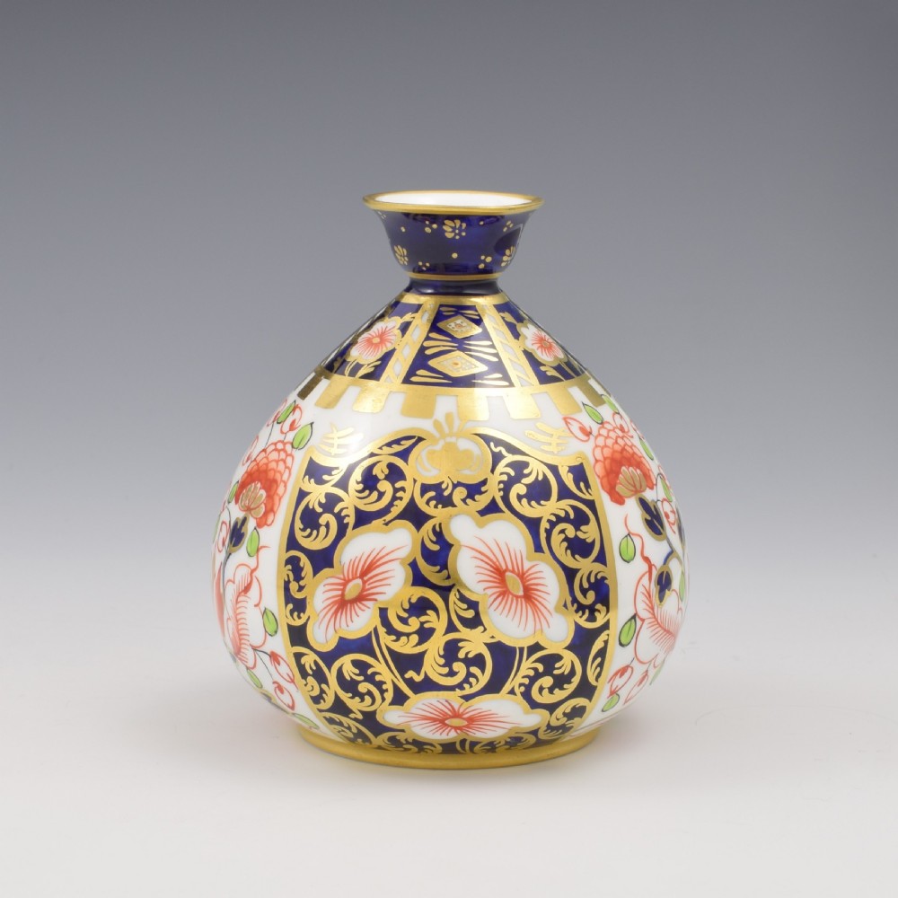 A globular Edwardian Royal Crown Derby porcelain bud vase decorated in an Imari pattern of cobalt blue, iron red flowers, green leaves, and gold gilding. View II