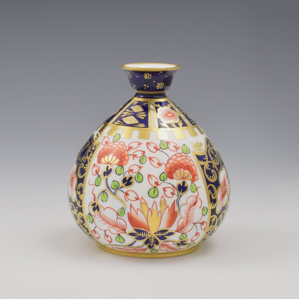 A globular Edwardian Royal Crown Derby porcelain bud vase decorated in an Imari pattern of cobalt blue, iron red flowers, green leaves, and gold gilding. View III