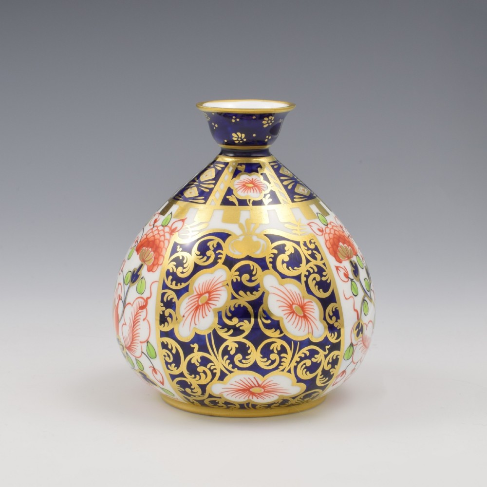 A globular Edwardian Royal Crown Derby porcelain bud vase decorated in an Imari pattern of cobalt blue, iron red flowers, green leaves, and gold gilding. View IV