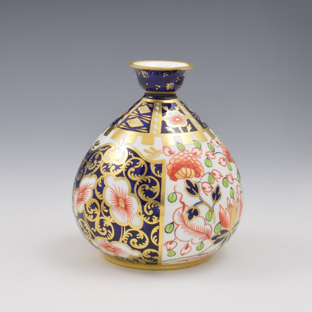 A globular Edwardian Royal Crown Derby porcelain bud vase decorated in an Imari pattern of cobalt blue, iron red flowers, green leaves, and gold gilding. View VIII