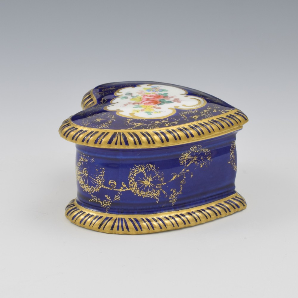 A heart-shaped cobalt blue porcelain jewellery box featuring a hand-painted floral cartouche and detailed gilding along ribbed edges. View VIII