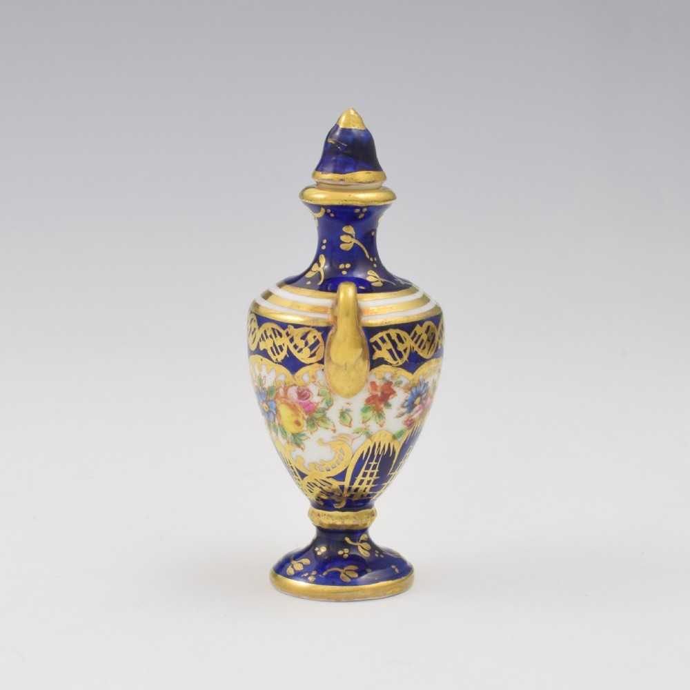 An Edwardian miniature cobalt blue porcelain scent bottle in urn form with twin gilt handles and hand-painted floral panels. View II